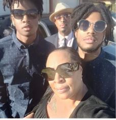 Harris with her twin sons. All are wearing sun glasses looking at the camera. 